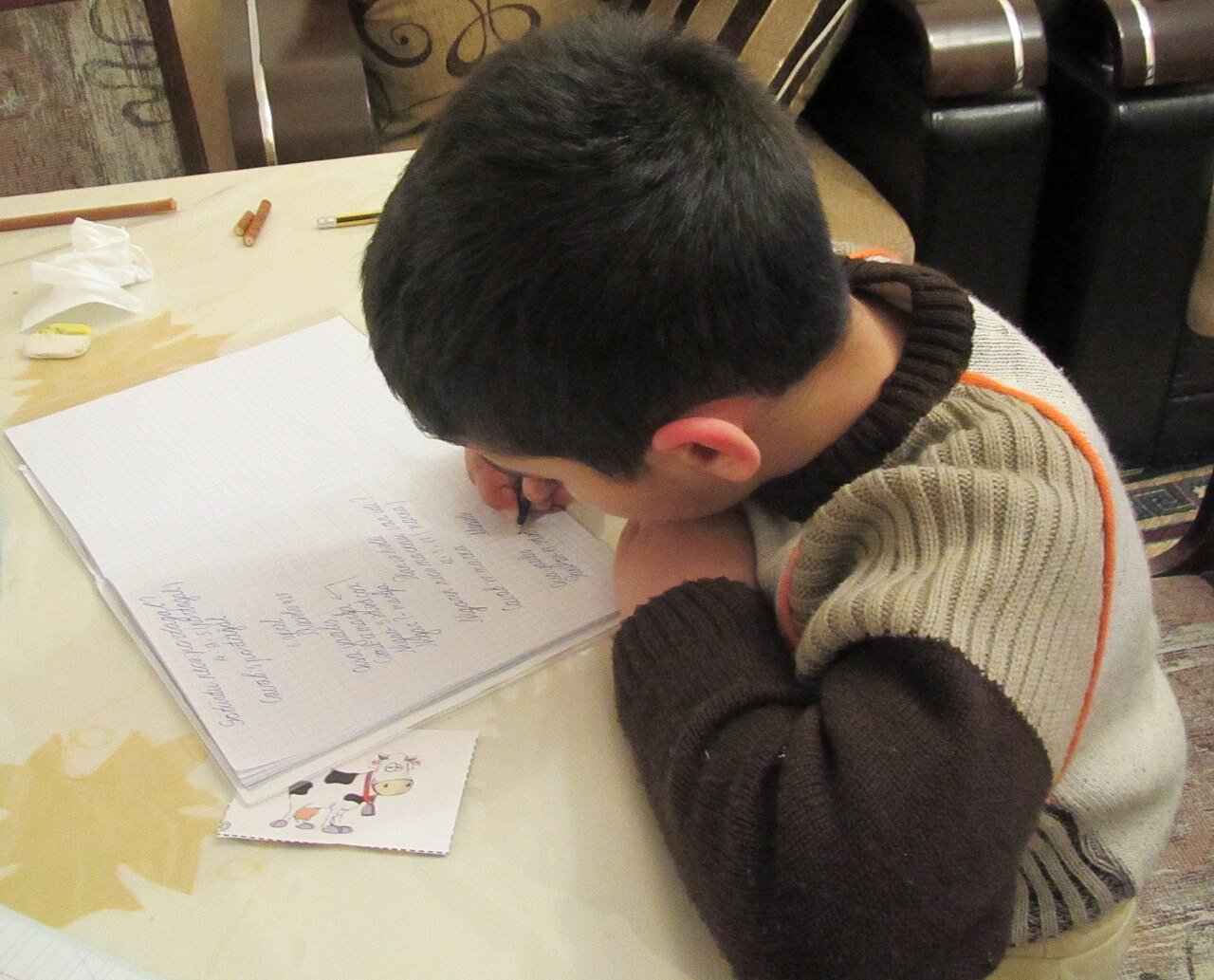 Estudante do ensino fundamental escrevendo em uma mesa